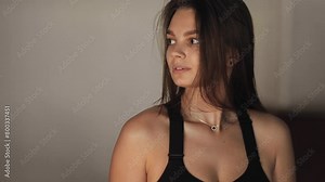 Close portrait of an attractive, athletic, bronze-skinned girl, model with dark hair, the girl looks down and straightens her hair, beauty, model look, fresh, young, shiny, skin glow, glamour, face