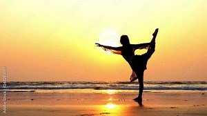 Silhouette of young sporty woman performing rhythmic gymnastics element on the beach at beautiful sunset