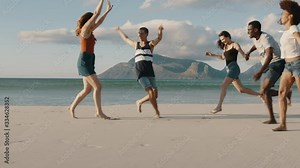 Group of multi-ethnic friends running and enjoying on the beach. Carefree young people having a great time together on a vacation.