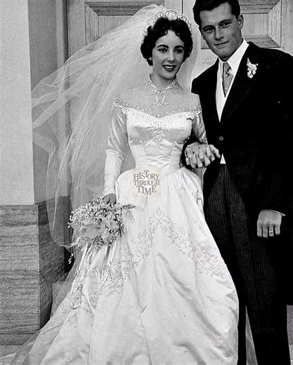 "Elizabeth Taylor weds her first husband, Conrad “Nicky” Hilton Jr., in California in May of 1950, marking one of Hollywood’s most anticipated society events. The ceremony took place at the Church of the Good Shepherd in Beverly Hills, attended by industry elites, family, and friends. Elizabeth, just 18, wore a satin gown designed by Helen Rose of MGM, adorned with seed pearls and a sweeping train, a gift from the studio. Hilton, heir to the famous hotel empire, met Elizabeth at a Los Angeles pa