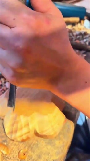 carving a flower pattern into a wood block with a sharp gouge tool