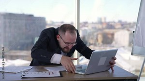 Man doing funny faces sitting in front of laptop. Mad businessman typing nervously with fingers on keyboard and looking to the sides. Entrepreneur with insane face in office.