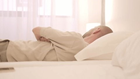 Tired Sleep-deprived young man lies in bed struggles with insomnia, unable to sleep. Sleep disorder, overthinking, restless thoughts deprivation, mental health, sleeping issues, disturbances