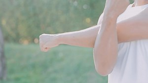 Download Athletic runner doing stretching exercise, preparing for running in the nature with the city in background. Healthy lifestyle for free