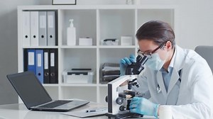 Médecin professionnel travaillant en laboratoire au microscope.