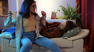 Playful domestic scene, Young couple shares laugh while engaging in a light-hearted wrestling match on their couch.