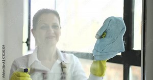 Woman housekeeper washing glass window with detergent and rag 4k movie slow motion. Cleaning services for apartments and offices concept