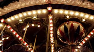 A glowing decoration of rotating carousel on a night. Evening in the amusement park. Old retro merry-go-round is turn s with illuminated light bulbs. Stock Video
