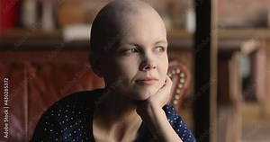 Head shot sincere smiling young hairless after oncology treatment woman thinking of effective illness treatment, visualizing healthy future, feeling hope and inner strength for fighting with disease.