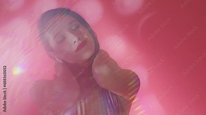 Young beautiful woman enjoys music and dancing at disco party. Portrait of female music lover using earphones and moving sensually and slowly at pink background