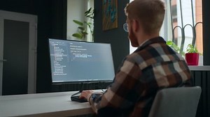 data scientist writing code, working in office IT company or freelancer in home, view over shoulder