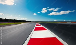 A sharp curve on an empty race track under a bright blue sky, emphasizing speed, precision, and the thrill of motorsport