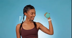 Woman, face and dumbbell in studio, fitness and workout for bicep muscle, pride and power by blue background. Girl bodybuilder, performance and strong for health, exercise and portrait for wellness