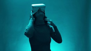 Mature woman uses virtual or augmented reality glasses in magic atmosphere of teal blue light. Female model with VR headset user in digital interactive performance, entertainment of future, technology