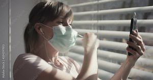 Woman takes off face mask and have a video call at the end of self isolation quarantine and coronavirus pandemic close up