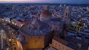 famous cathedral in Cadiz, resort in Andalucia, Spain, after sunset with night lights, flying around European historic cathedral on the coast of the ocean