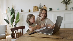 Free stock video - A pretty blonde little girl reads the lesson on the laptop screen while she smilingly listens to it
