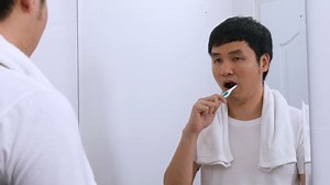 Man using toothbrush to brushing teeth in the bathroom mirror