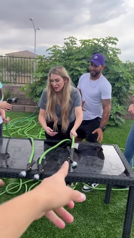 Happy friends play water in hose game.