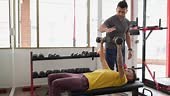 Personal trainer teaching student how to bench press correctly at the...