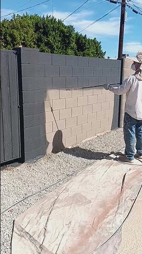 Spray painting a cinder block wall.