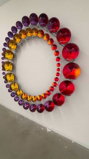 The two concentric rings of colourful glass spheres that form 'Successful coexistence beyond earth', 2025, both progress around their circumferences from small to large. The biggest spheres are located at opposite sides of the inner and outer rings; however, so that the two circles are counterposed to one another, creating balance and a subtle sense of spiralling motion. As viewers move around to examine the reflective interiors of the spheres, the artwork changes constantly. Seen from the front
