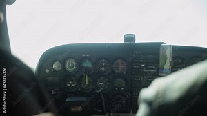 The inside plane's black dashboard with indicators of altitude above the ground, speed, engine. A handsome pilot controls a sporty four-seater aircraft. Flight in the sky, airspace