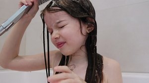 clip-1084439035-little-girl-washes-her-hair-rinses-off