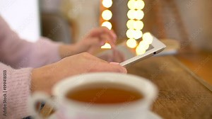 Casual woman sitting inside a coffee shop. Woman using tablet at a cafe with cofee or tea. close-up. 4 k. Young people using technology in cafe