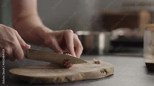 Slow motion man slicing salami on olive board