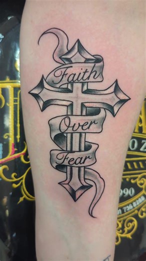 Black and grey shaded cross with Faith Over Fear in the banner #cross #faithoverfear #blackandgreytattoo #crosstattoo #tattooartist