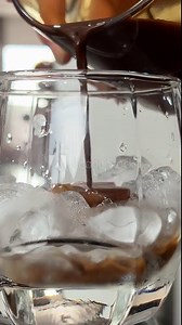Pouring Cold Brewed Coffee over Ice. Making ice latte. Cold brew with ice and milk. Pouring thick coffee into ice