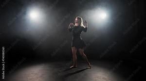 Woman choreographer dancing jumping. Blonde hard-working female ballerina dances in black dress in studio on stage. Performing dance element perform ballet bouncing in air. Classical choreography.