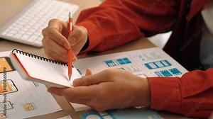 Startup company employee planning for user interface prototype for mobile application or website in office with model of program on desk. UX UI designer consider user friendly interface plan. Synergic