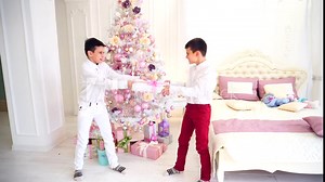 Childish pranks of two brothers of twins and innocent fight for Christmas present in bedroom with Christmas tree.