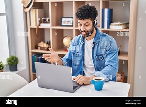 Arab man doing video call using computer laptop celebrating achievement with happy smile and winner expression with raised hand Stock Photo - Alamy