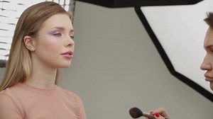 Backstage of the photo shoot: Make-up artist applies makeup on beautiful white model. Tutorial makeup master class.