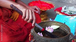 A bowl with holy water with lotus flowers for religious ritual in Angkor Wat temple. Buddist monk blesses people by splashing holy water into their faces