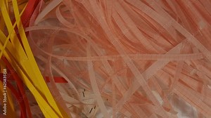 Close up of shredded paper ejected from paper shredder. Strips of red, yellow and graph paper.