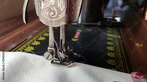 Close up shot of Indian poor old woman stitching cloths on a sewing machine, slow motion