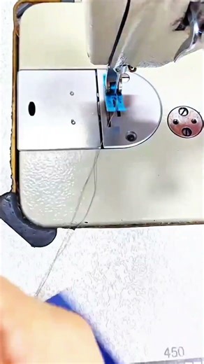 Blue fabric gathers under presser foot needle hums pleats form hands guide flow