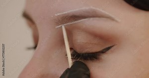 Master applies white markings to correct shape of eyebrows with a special brush. Building the Shape of Eyebrows, Beauty Salon. Close Up. Preparation for tattooing. Create permanent eyebrow makeup.