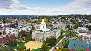 Aerial establishing shot of Concord with slow forward motion past New Hampshire State House golden dome. The capitol houses the New Hampshire General Court, Governor, and Executive Council.