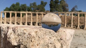 crystal ball reflection against ancient ruins of roman city, columns, hand holding