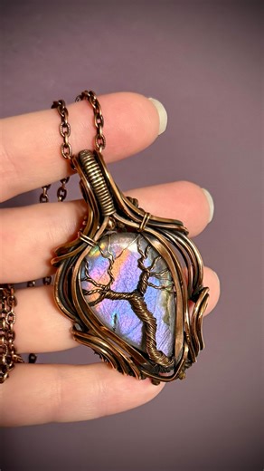 Jewelry designs by Cambrie on Instagram: "Labradorite is one of the most magical stones with their flashes of colors that never disappoint! Personally I’m a sucker for the purples, but this one is even more gorgeous with that streak of orange in there 🧡 Wrapped in oxidized copper with a tree of life design, this beauty will be available in my shop today at 3:30 PST 💜🧡 #labradorite #uniquejewelrydesign #wirewrap"