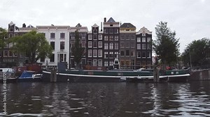 Amsterdam houseboats and apartment buildings filmed while sailing on a canal.