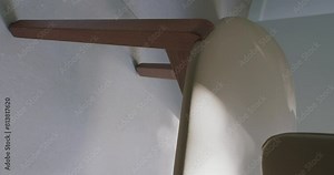 Close-up view of a modern chair featuring stylish wooden arms and a textured white seat. Ideal for interior design themes. Modern Chair Design with Wooden Arms and White Texture. Vertical video.