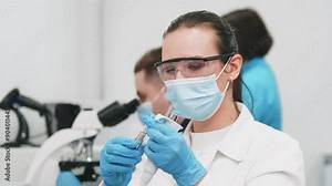 Scientist in a modern medical lab examines molecular samples under a microscope. Microbiologist works with advanced technological equipment in a state-of-the-art laboratory