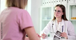 Woman doctor listens to patient complaints examining ultrasound results. Specialist analyzes client words writing conclusions slow motion