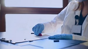 Female doctor in medicine gloves with stamp does the medical report working at hospital.